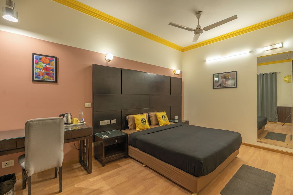 A bedroom with a bed, desk, chair, and a ceiling fan.
