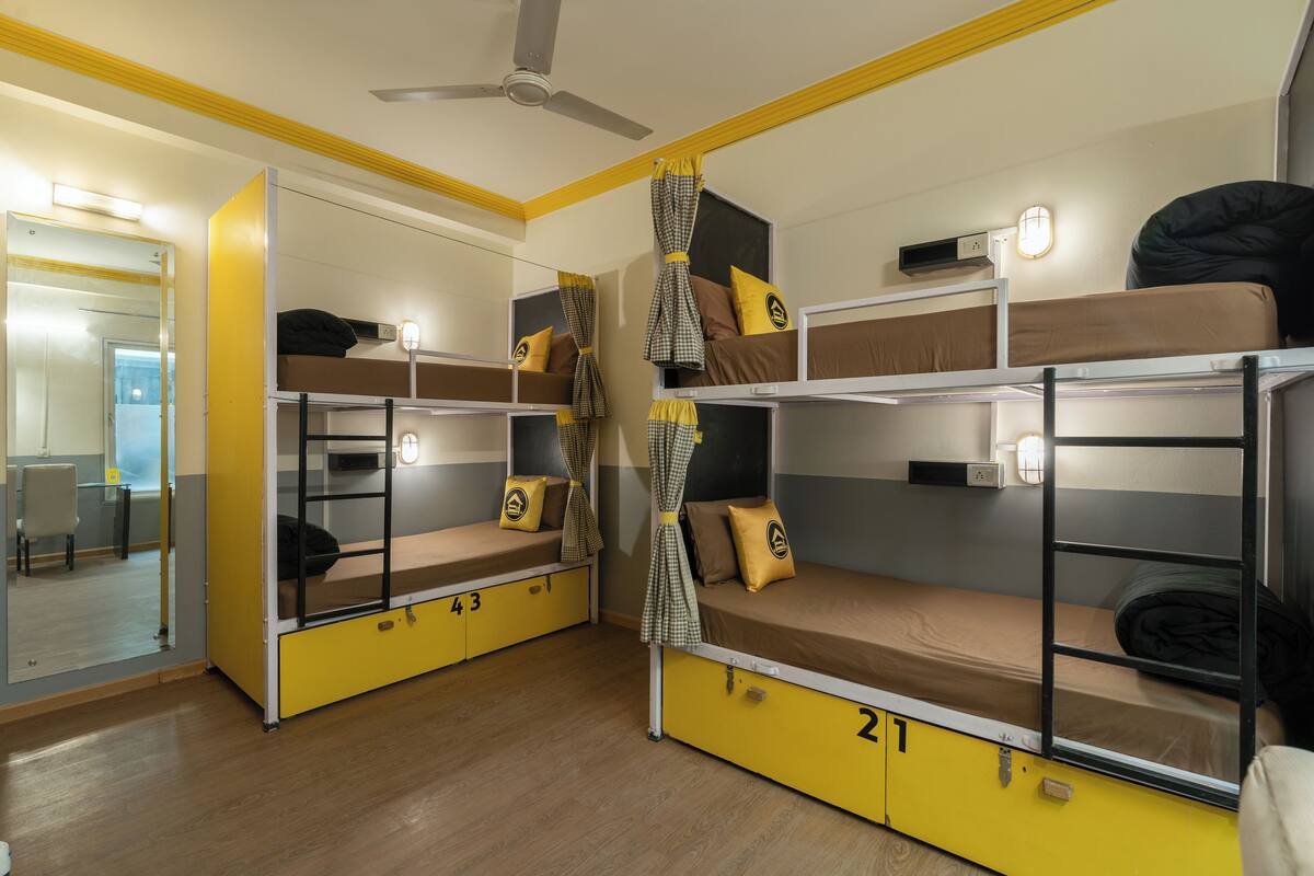 A dormitory room with bunk beds, each with a number, and a mirror on the left wall.