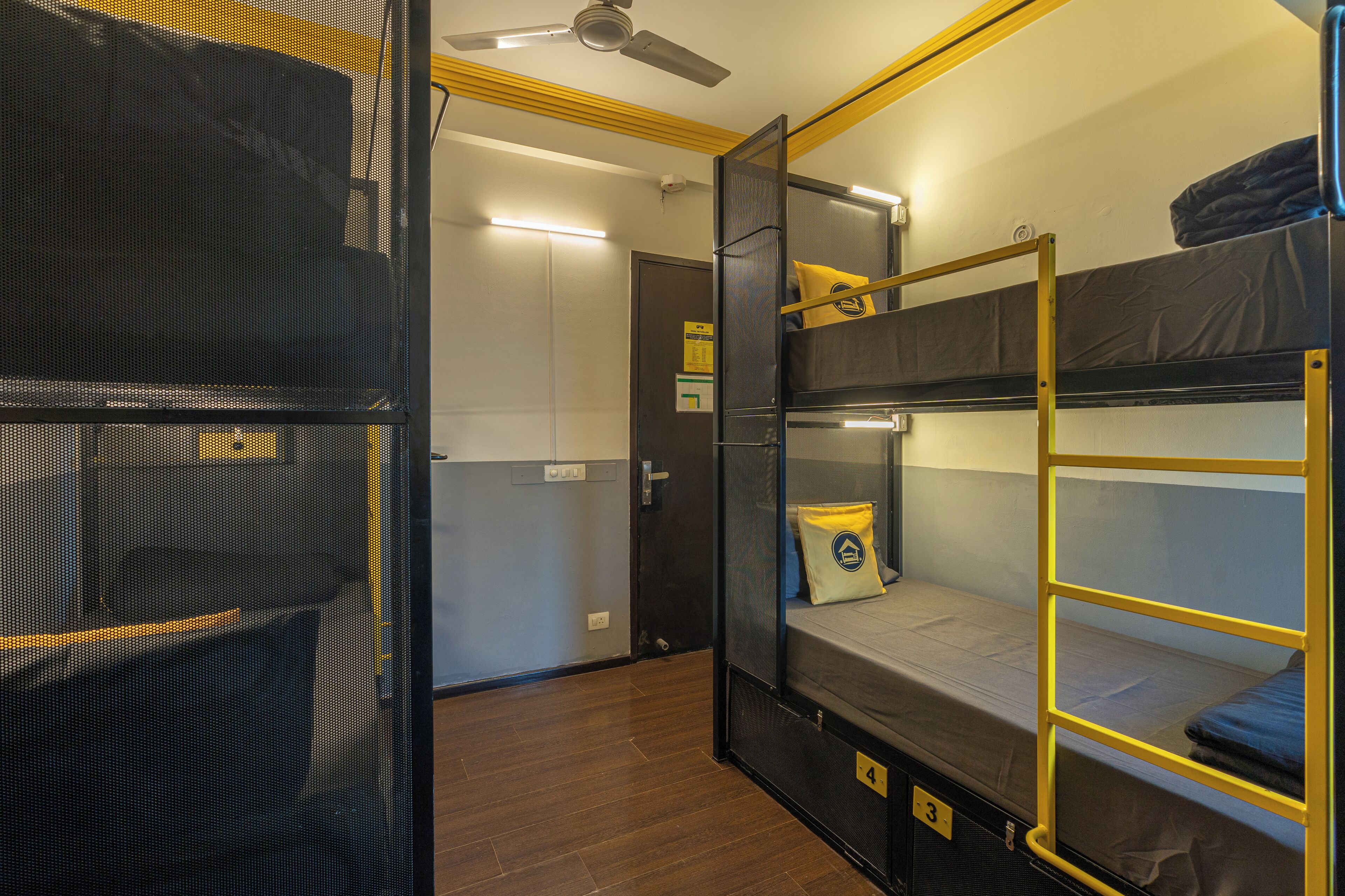 A bunk bed room with a ceiling fan, a door, and a light switch on the wall.