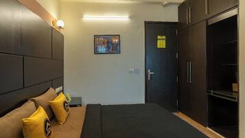 A hotel room with a bed, a wardrobe, a nightstand, and a wall-mounted light fixture.