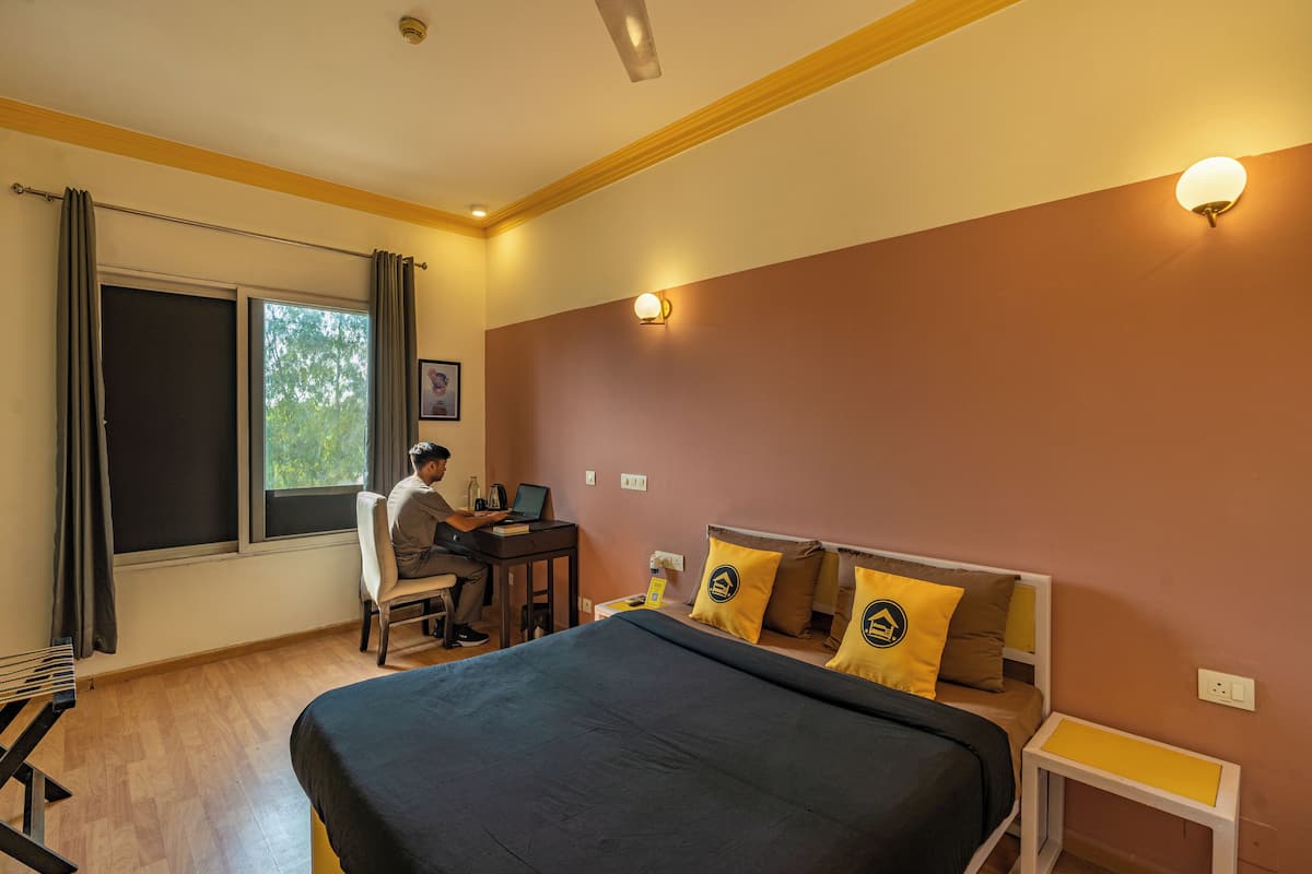 A hotel room with a bed, a desk, and a chair.