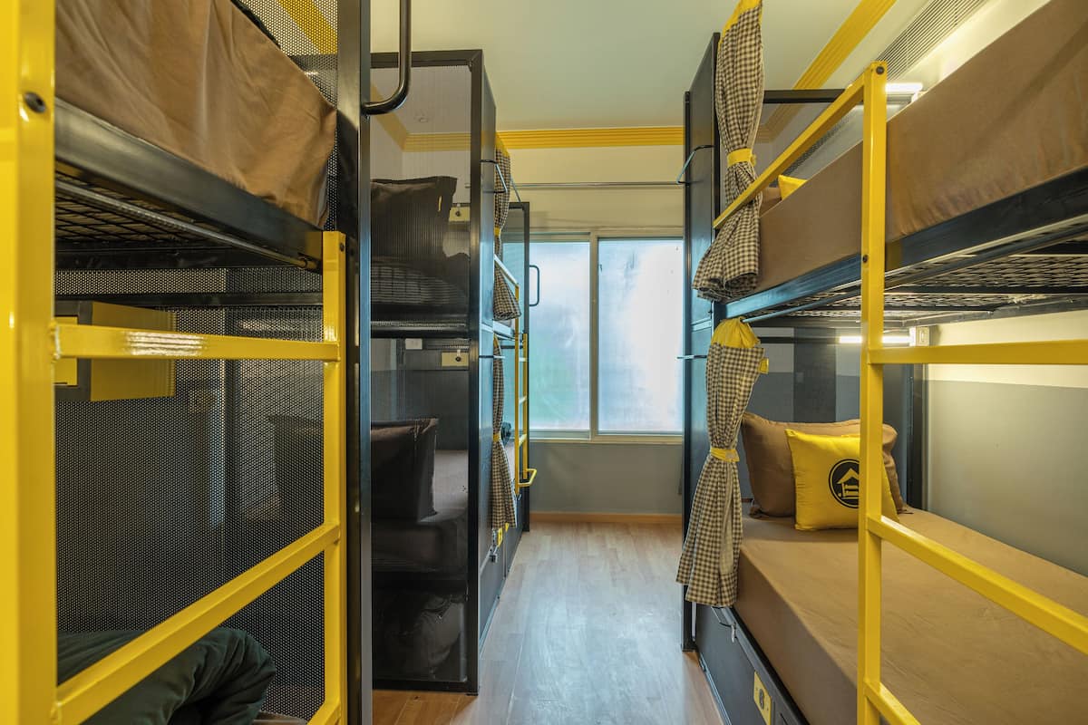 A train compartment with bunk beds, a window, and a wooden floor.