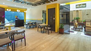 A modern restaurant with a wooden floor, yellow accents, and a staff-only door. - The Hosteller Delhi (New Delhi)