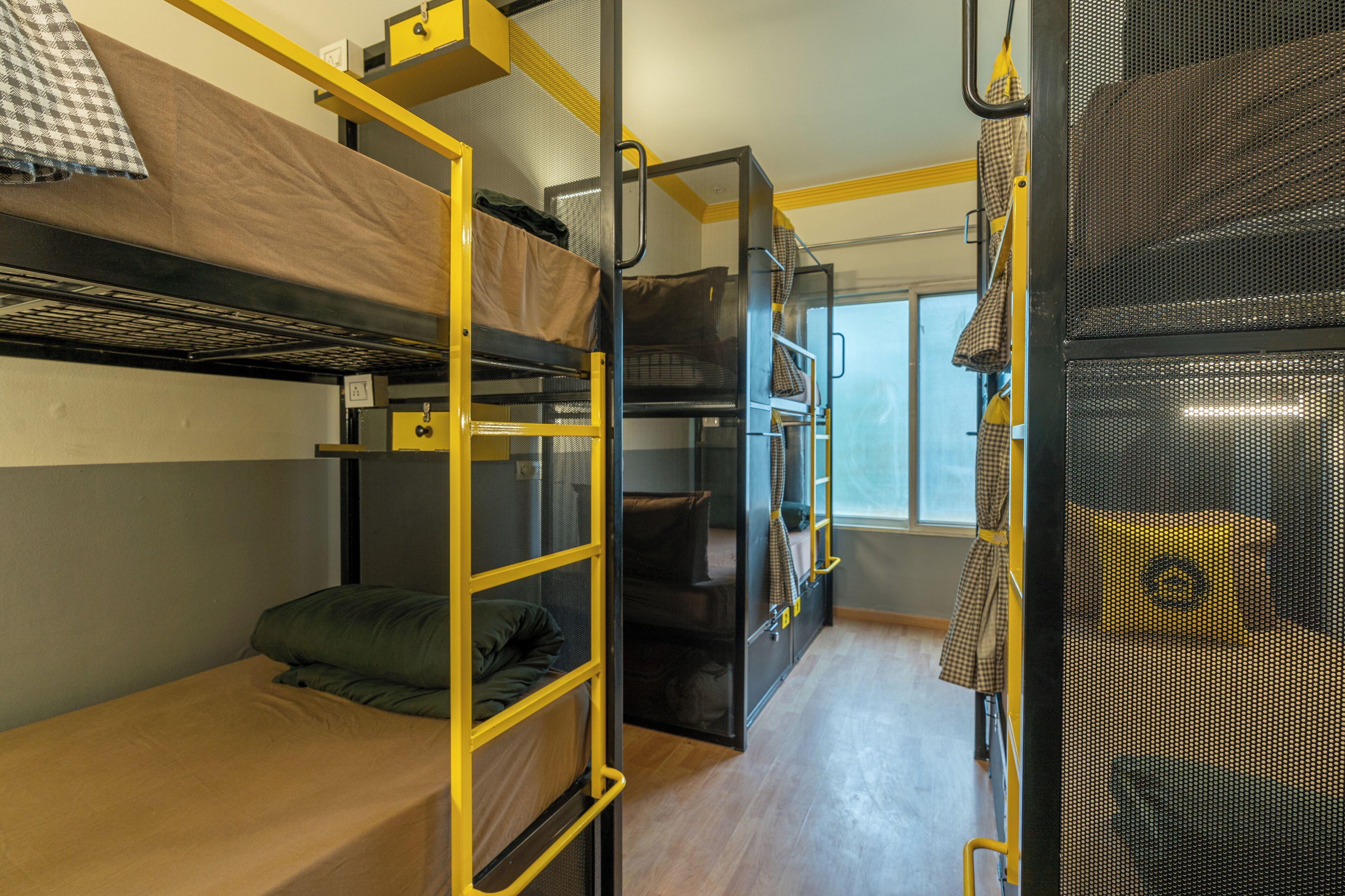 A dormitory room with bunk beds, a ladder, and a window.