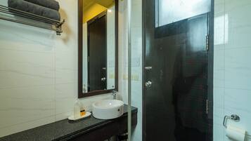 A bathroom with a white sink, dark countertop, and a glass shower enclosure.