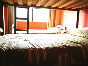 Quarto com uma cama, janela e teto de madeira.