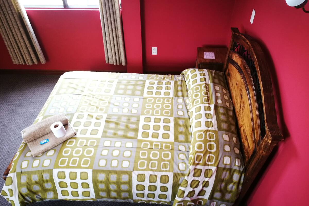A bed with a checkered bedspread, a wooden headboard, and a small bedside table with a lamp.