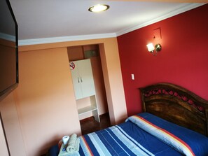 Quarto com cama, guarda-roupa e luminária na parede.