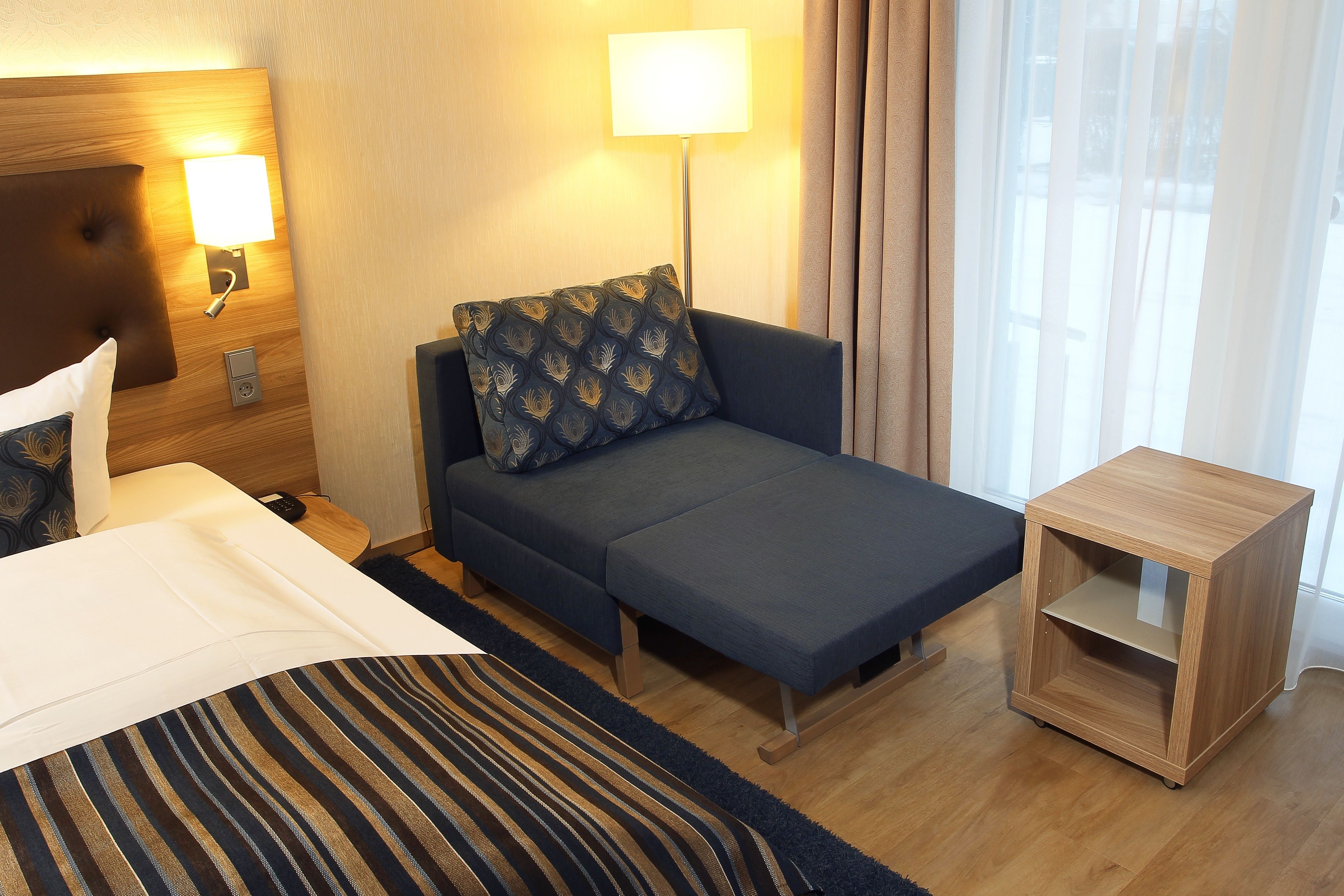 Ein Hotelzimmer mit Bett, Sofa, Nachttisch und Lampe.
