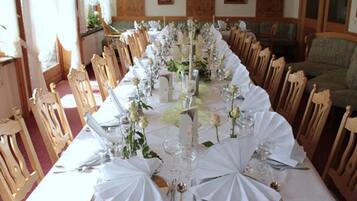 Una larga mesa de comedor con manteles blancos, centros de mesa florales y cubiertos dorados.