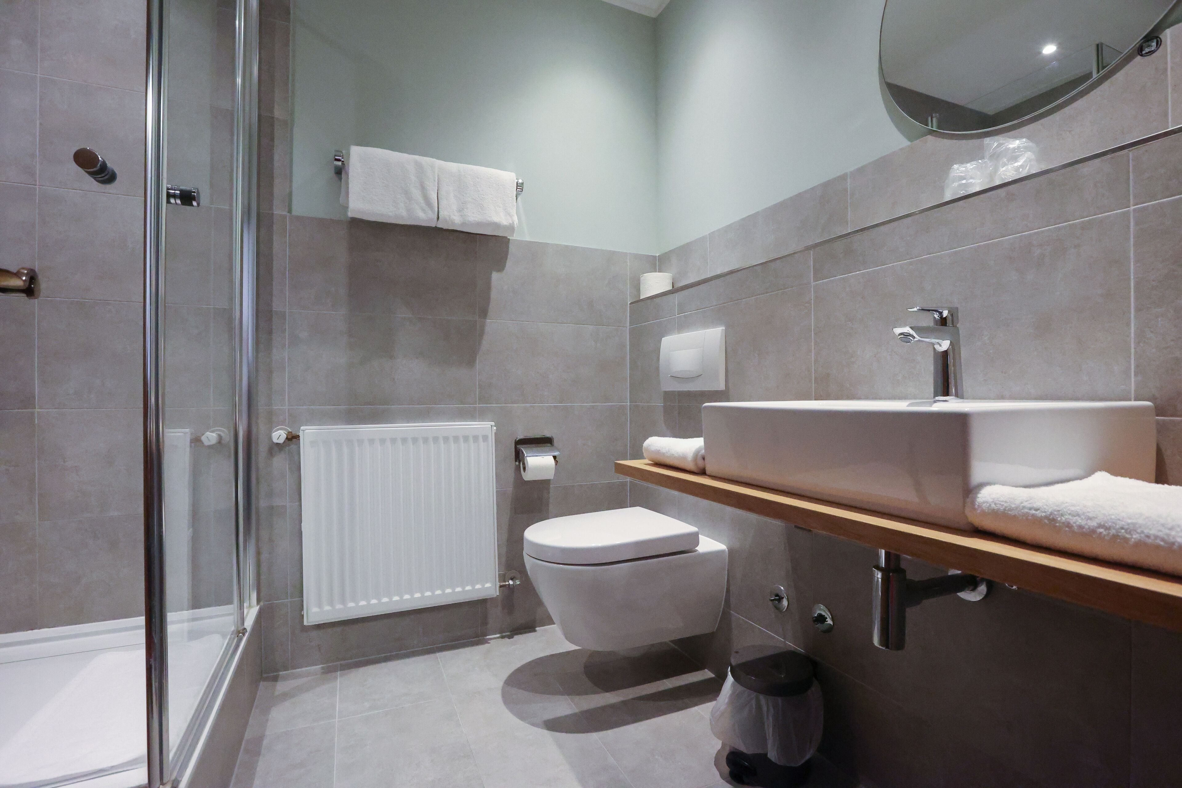 A modern bathroom with a glass shower enclosure, a white toilet, a sink with a mirror, and a towel rack.
