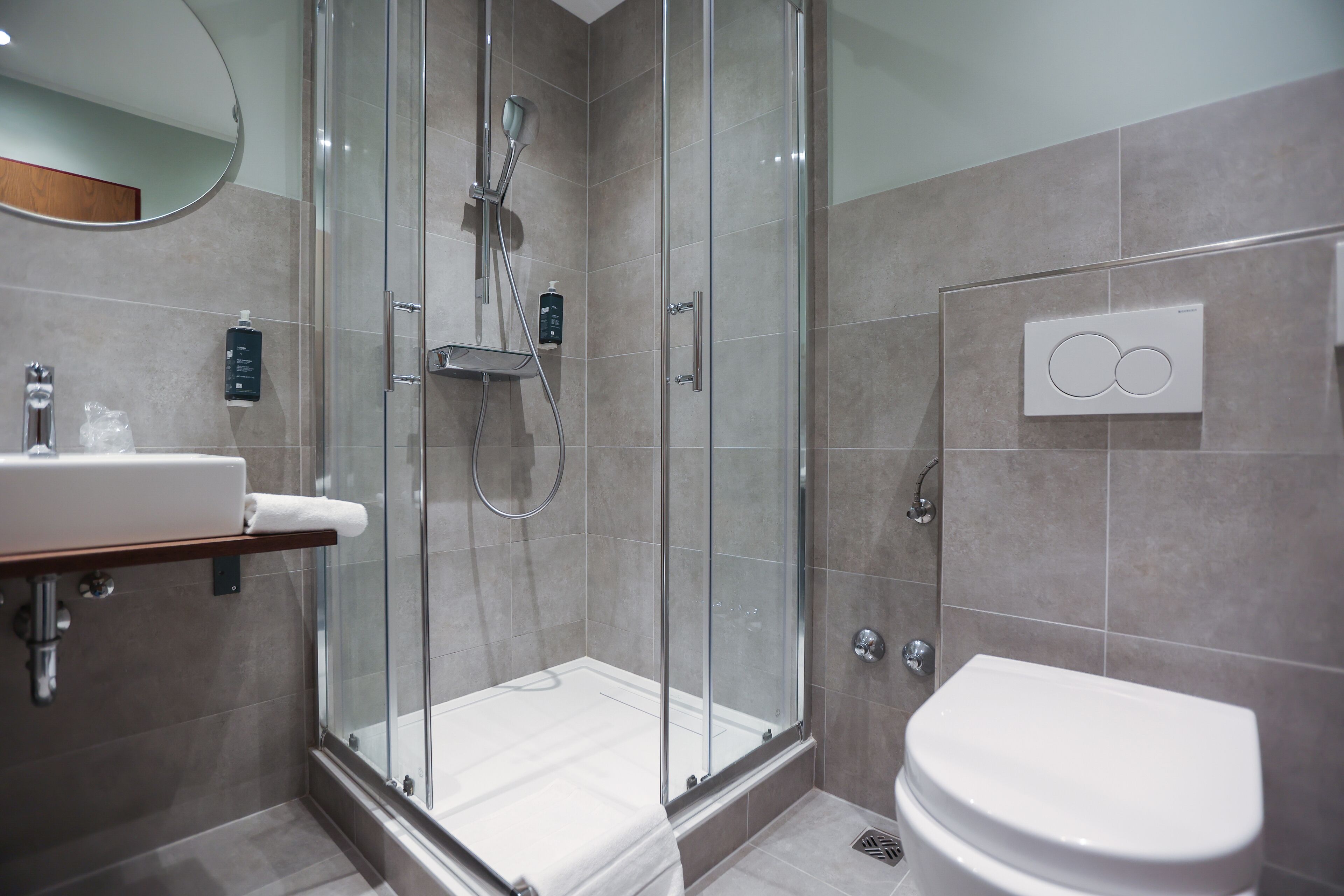 A modern bathroom with a glass-enclosed shower, a white sink, and a toilet.