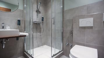 A modern bathroom with a glass-enclosed shower, a white sink, and a toilet.