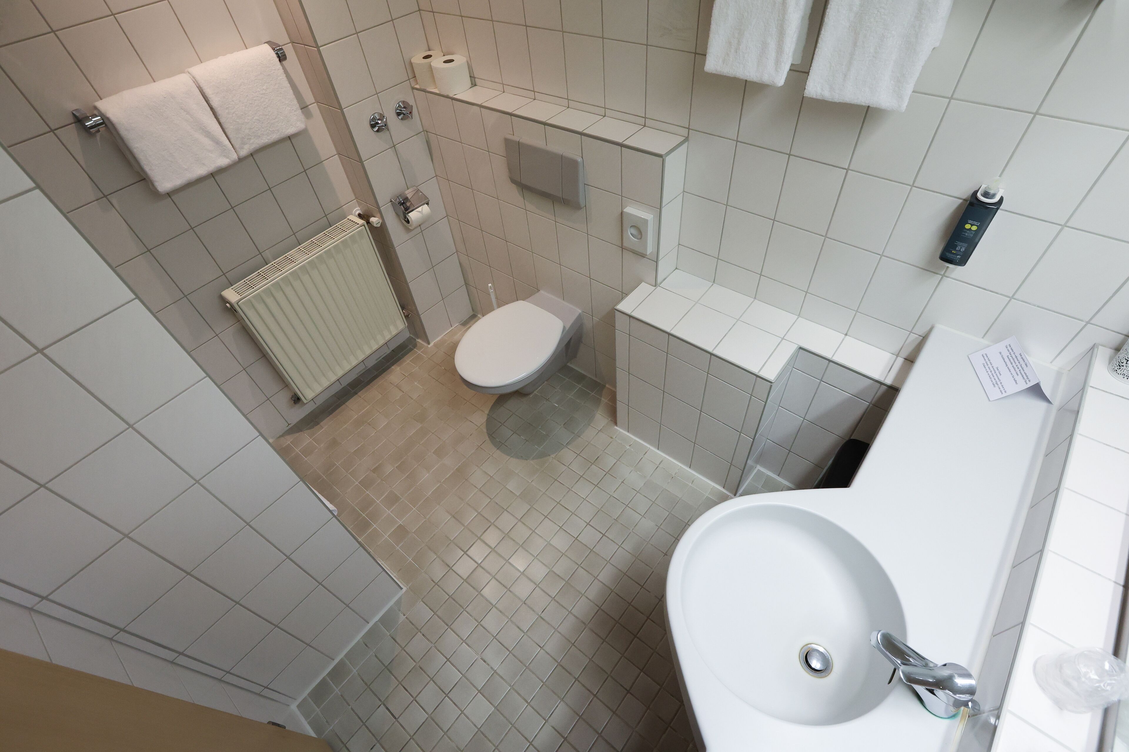 Een moderne badkamer met toilet, wastafel en handdoekhouder.