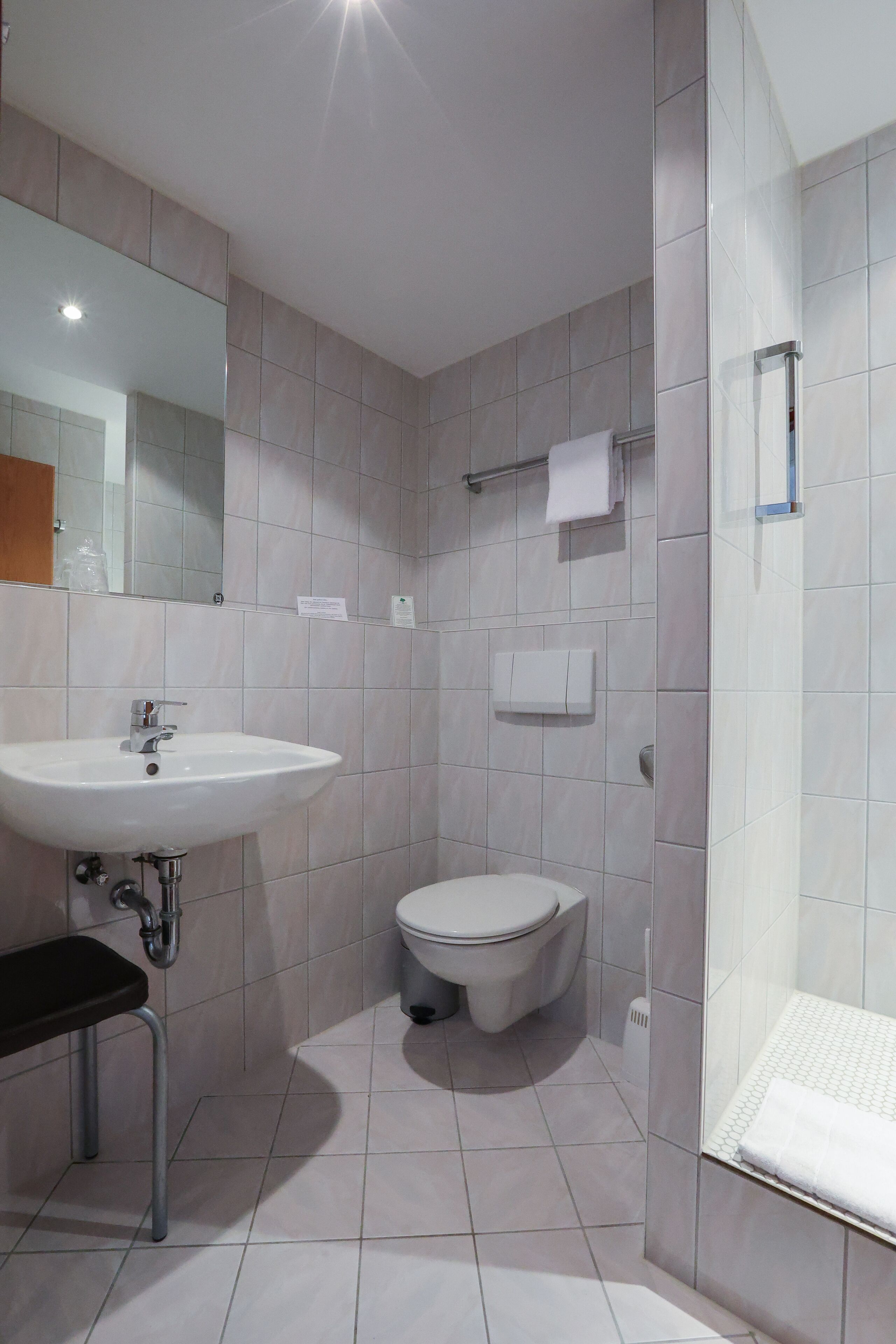 A modern bathroom with a white sink, toilet, and shower.
