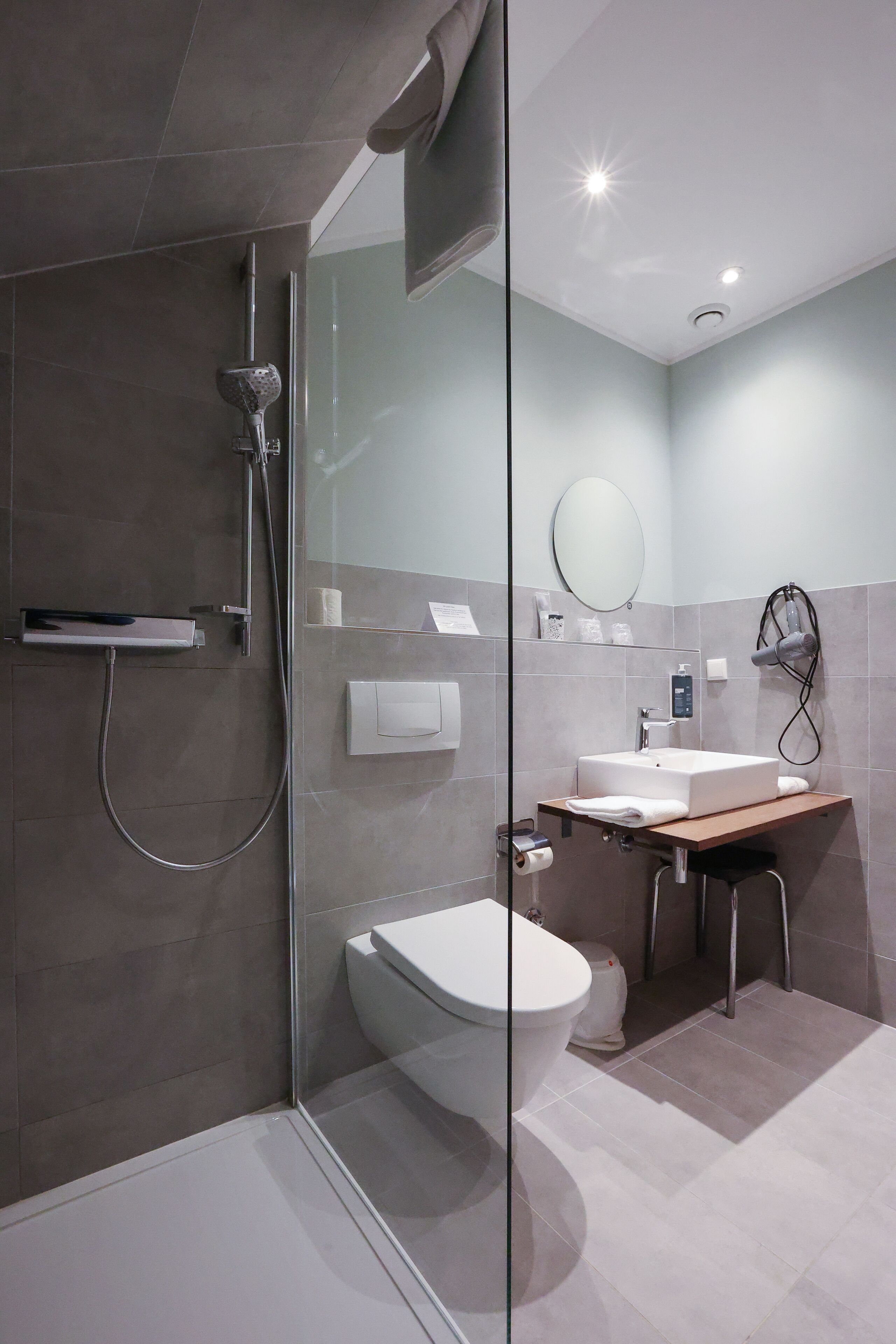 A modern bathroom with a glass shower enclosure, a white toilet, a sink with a mirror, and a towel rack.
