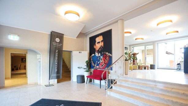 A spacious lobby with a modern staircase, a large poster, and a reception desk. - Arthotel ANA Panorama, Trademark Collection by Wyndham (Marktoberdorf)