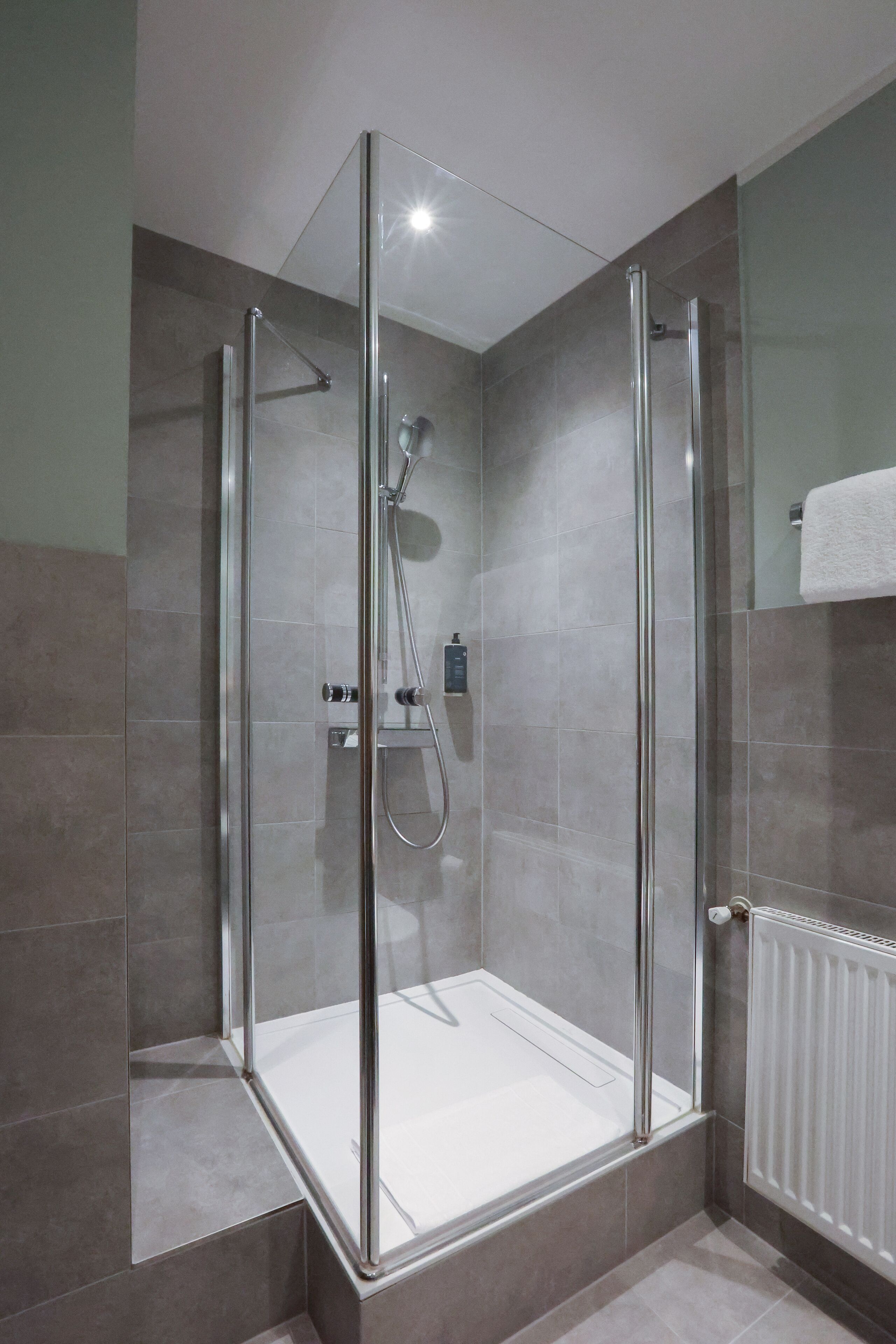A modern shower enclosure with glass doors and a white bathtub.