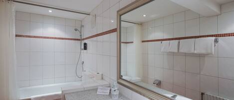 A bathroom with a white sink, a large mirror, and a shower area.