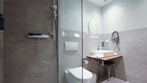 A modern bathroom with a glass shower enclosure, a toilet, a sink, and a mirror. - Arthotel ANA Panorama, Trademark Collection by Wyndham (Marktoberdorf)