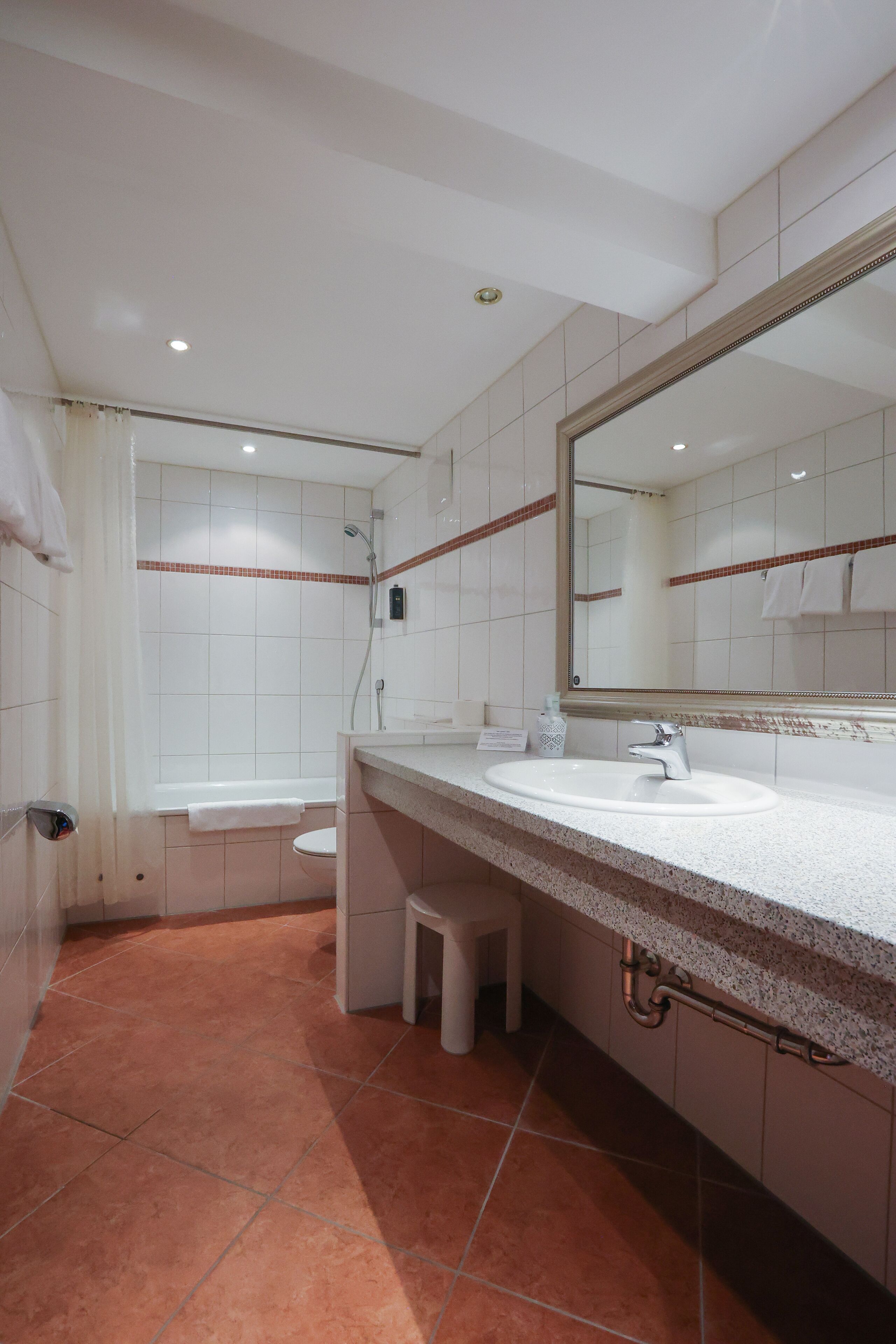 Une salle de bain moderne avec un grand miroir, un lavabo et une douche.