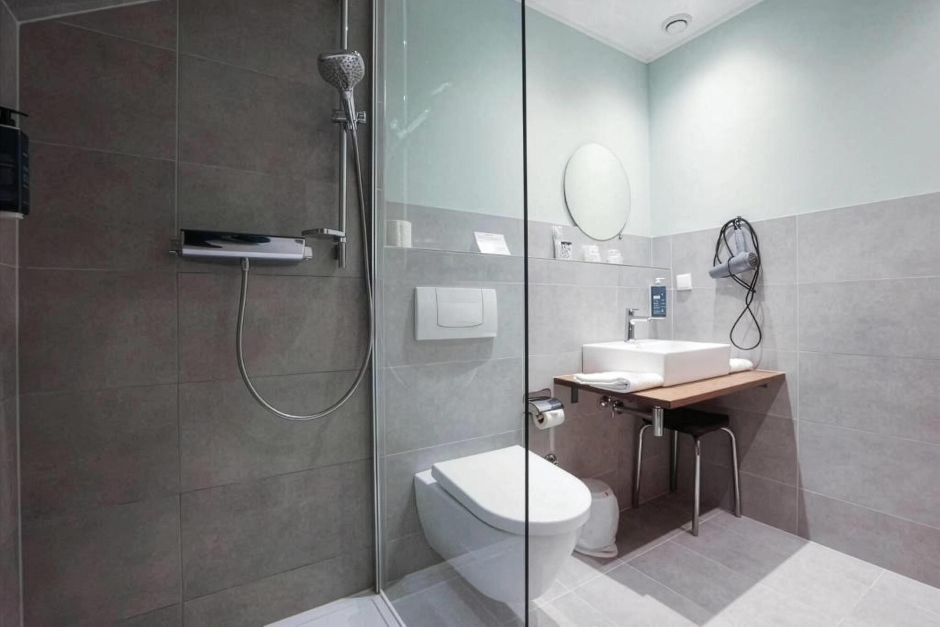 A modern bathroom with a glass shower enclosure, a toilet, a sink with a mirror, and a towel rack.