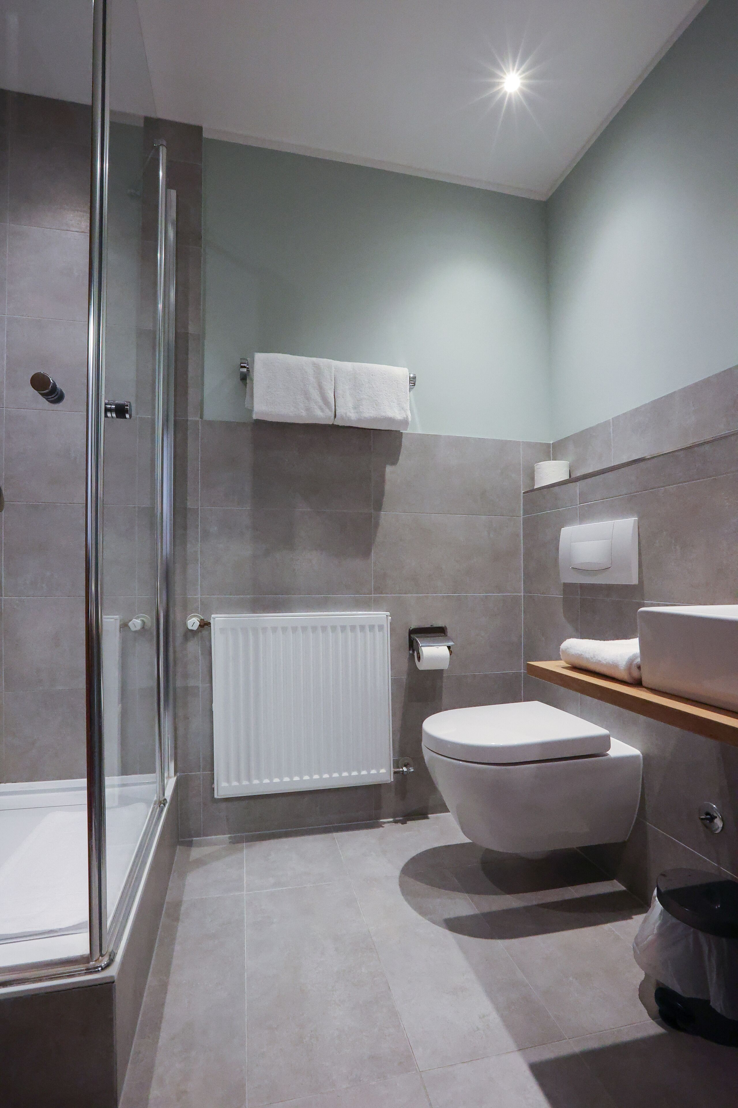 Une salle de bain moderne avec une douche à parois de verre, des toilettes, un lavabo avec un plan de travail et un porte-serviettes.