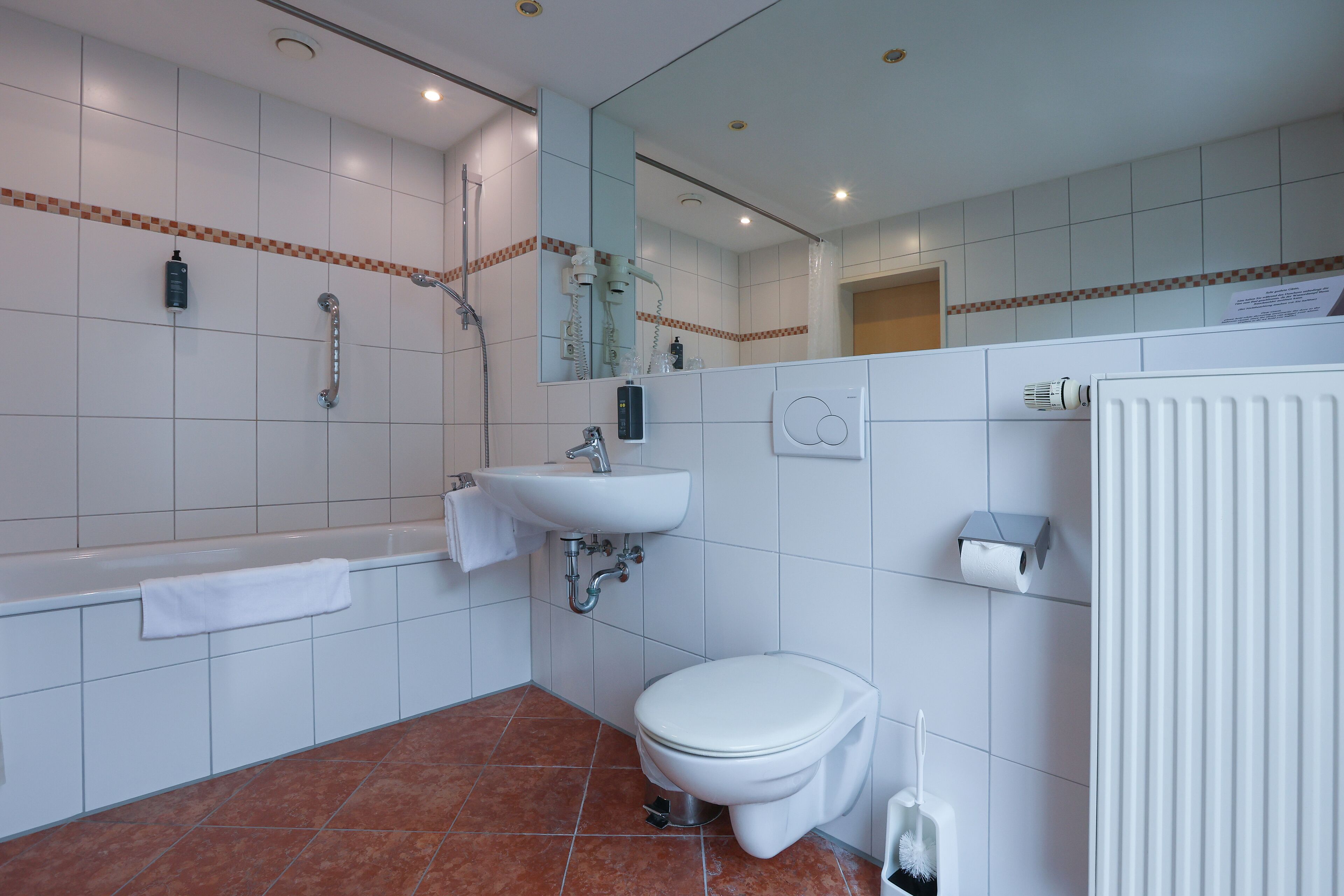 A modern bathroom with a bathtub, sink, toilet, and shower.