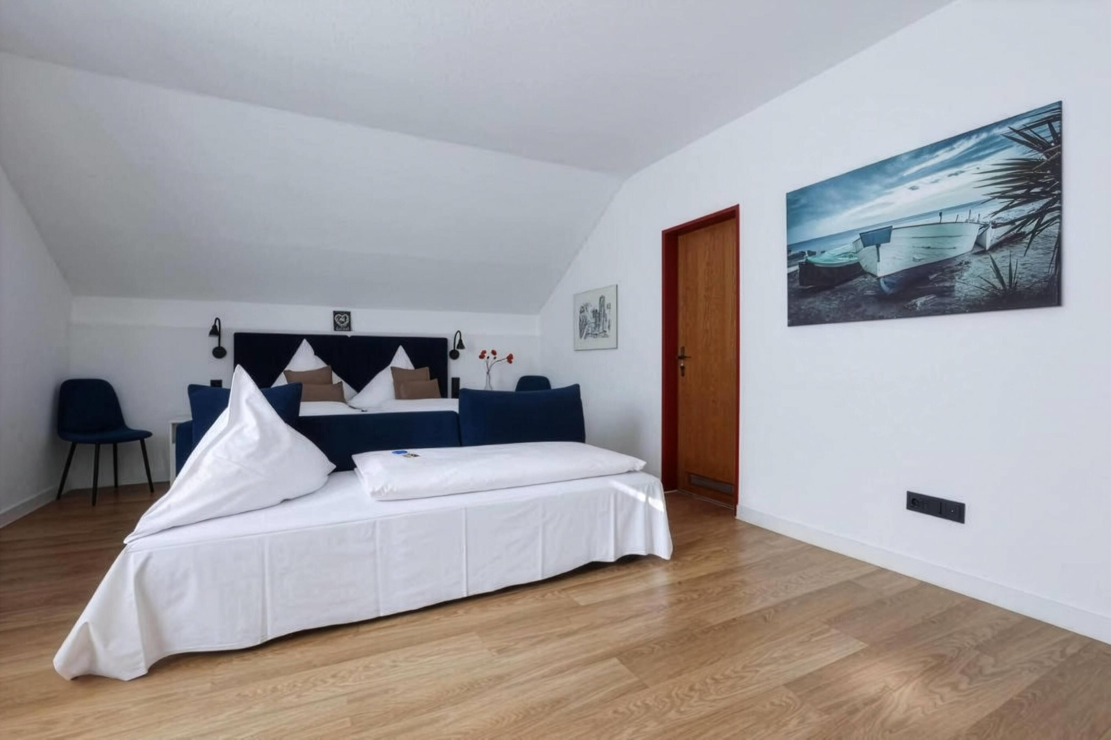 Ein Schlafzimmer mit einem Bett, einem Schreibtisch und einem Stuhl. Ein Gemälde hängt an der Wand.