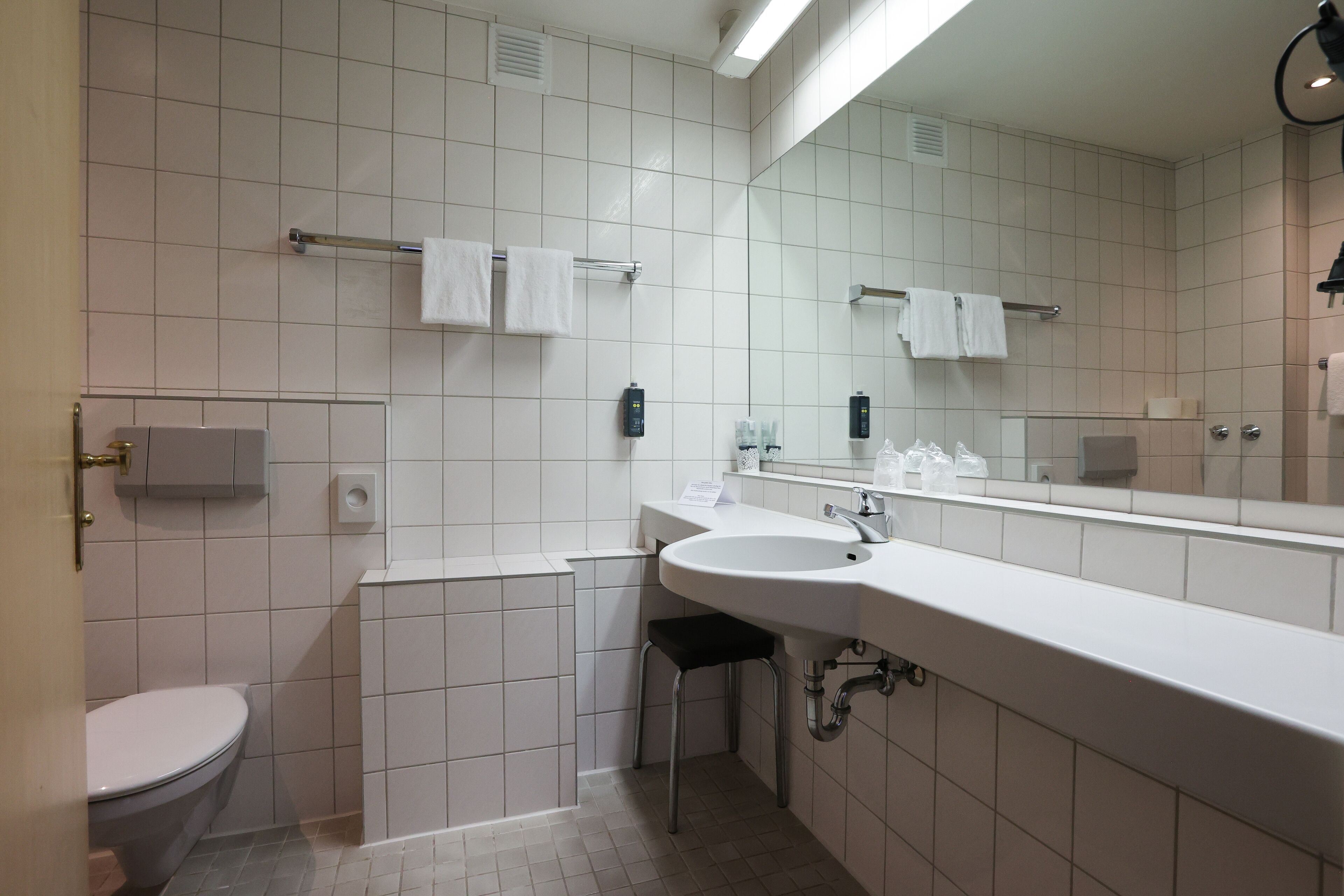 A modern bathroom with a toilet, sink, and mirror.