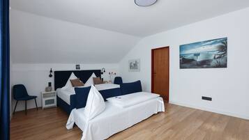 A bedroom with a bed, bedside table, chair, and artwork on the wall.
