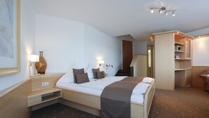 A hotel room with a bed, bedside tables, a lamp, a vase, and a wardrobe. - Arthotel ANA Panorama, Trademark Collection by Wyndham (Marktoberdorf)