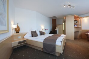 A hotel room with a bed, bedside tables, a lamp, a vase, and a wardrobe. - Arthotel ANA Panorama, Trademark Collection by Wyndham (Marktoberdorf)