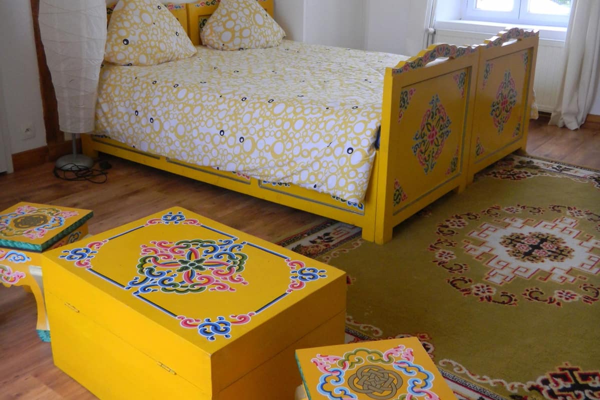 Une chambre à coucher avec un lit, une table de chevet, une commode et un tapis à motifs.