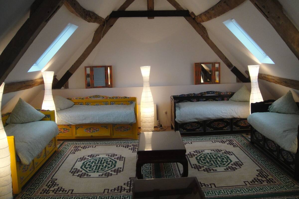 Une chambre mansardée chaleureuse, dotée de deux lits, d’une lucarne et d’un décor traditionnel.
