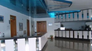 Eine moderne Hotellobby mit einer Rezeption, einer Glastrennwand und einem polierten Boden.