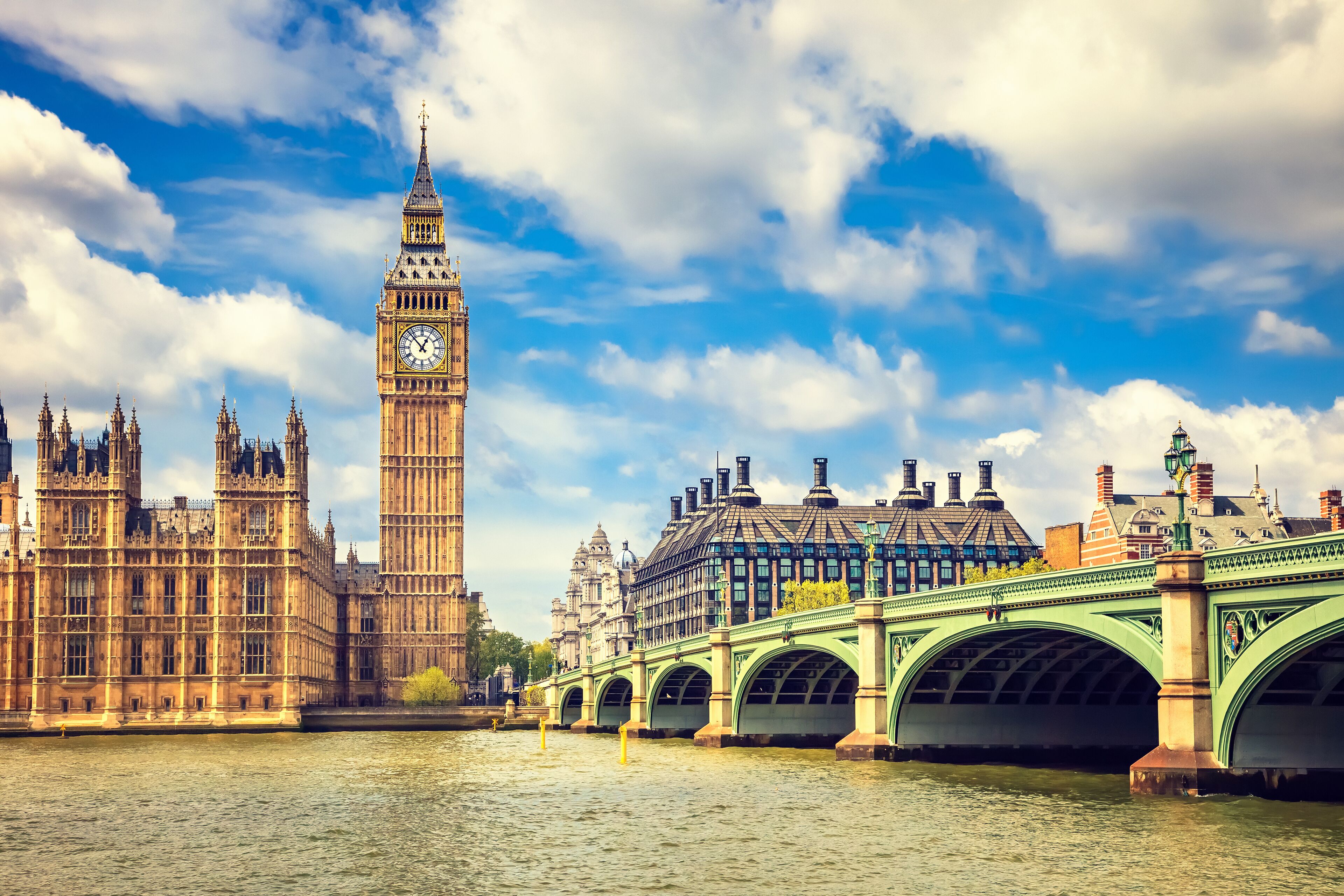 A river with a bridge, a clock tower, and historic buildings.