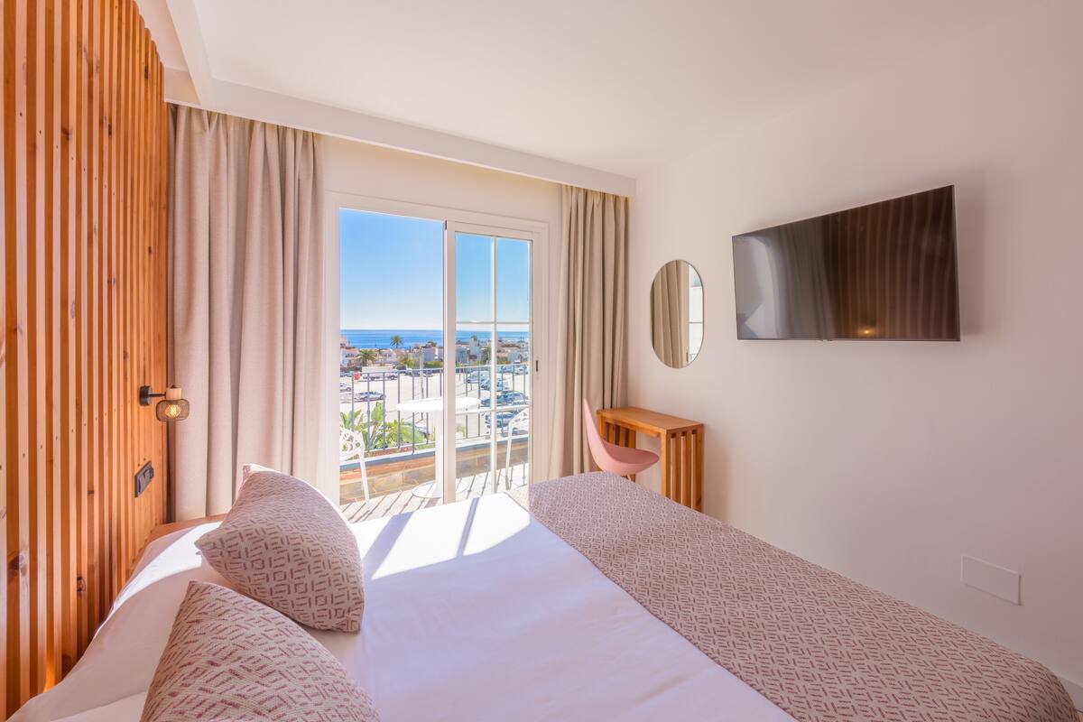 Une chambre d’hôtel avec un grand lit, un bureau, une chaise, une télévision et un balcon offrant une vue sur la ville.