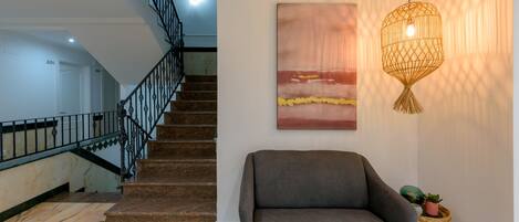 Una escalera con barandilla de metal, un sofá gris y una obra de arte colgada en la pared.