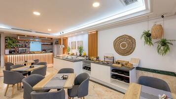 Un moderno vestíbulo de hotel con una zona de bar, asientos y un mostrador de buffet.