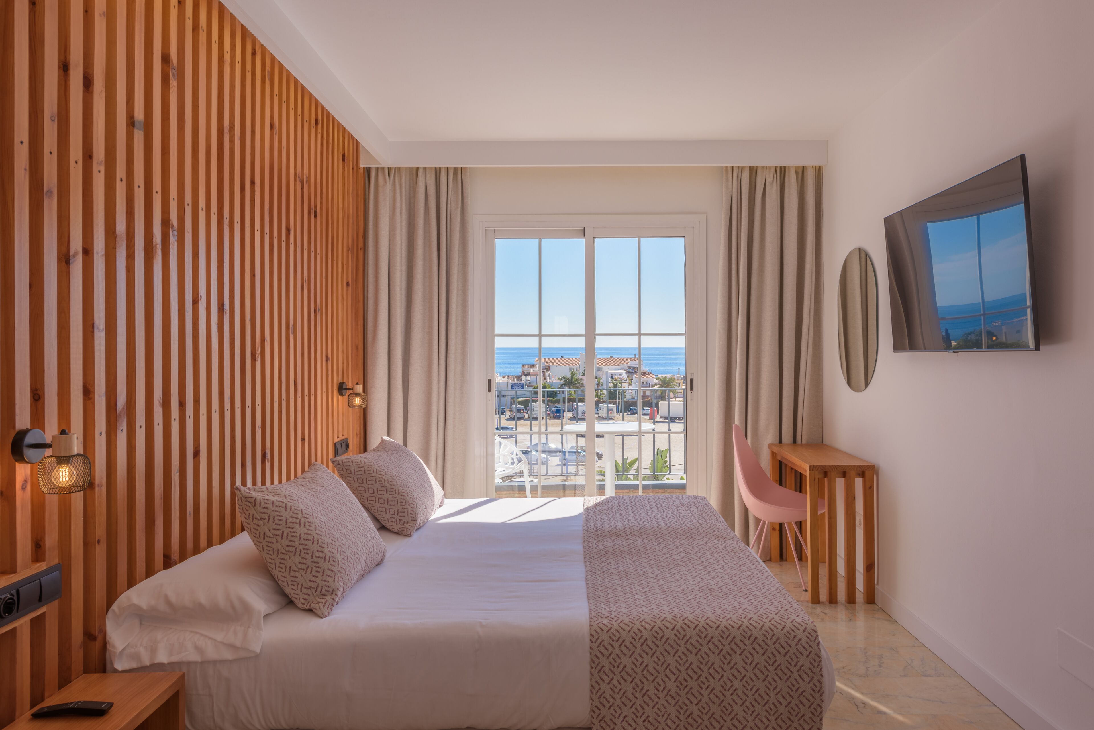 Une chambre d’hôtel avec un grand lit, un bureau, une chaise et une vue sur la mer.