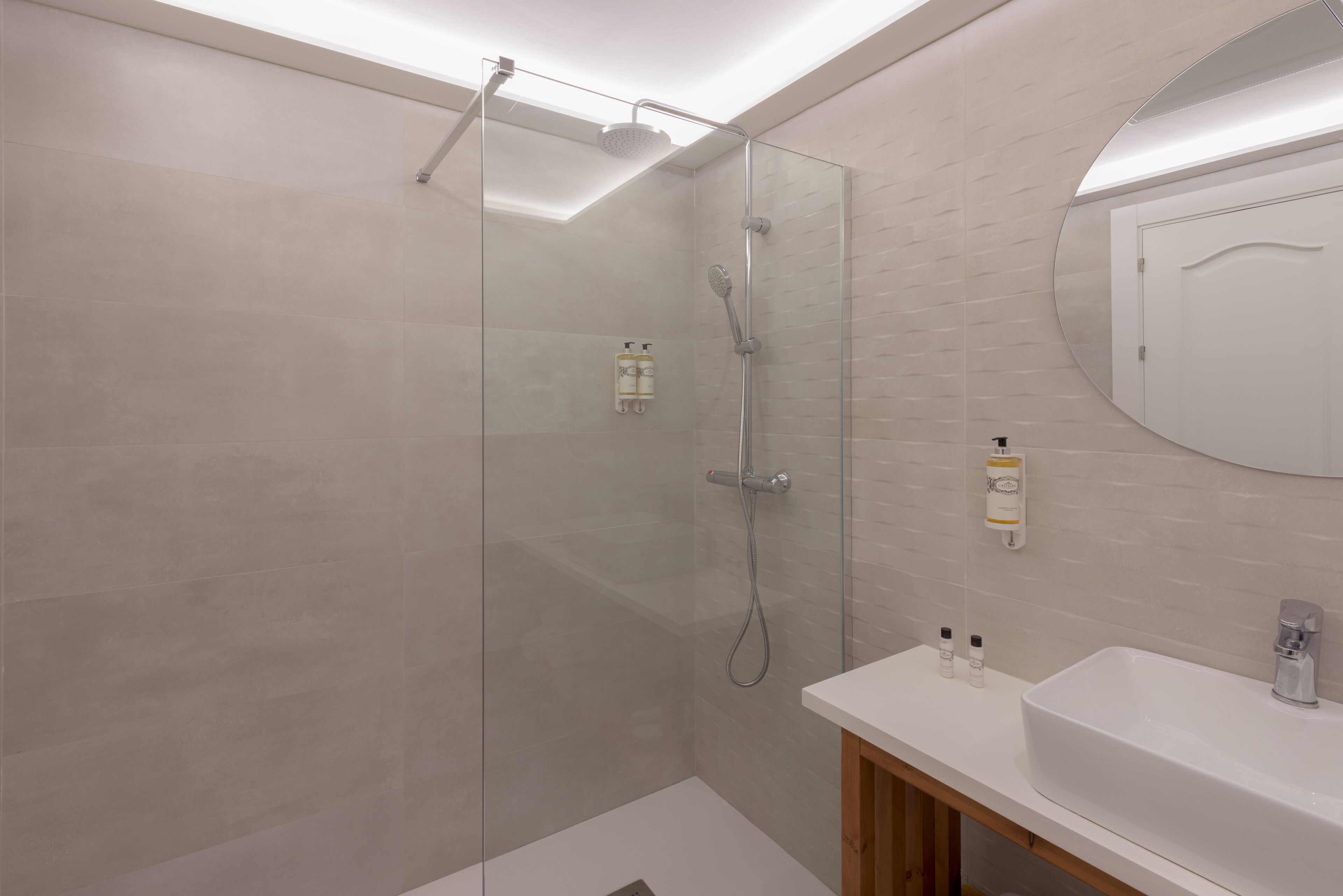 Une salle de bain moderne avec une douche à parois de verre, un lavabo blanc et un miroir.