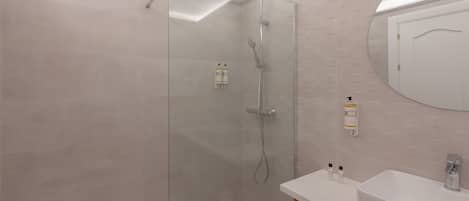 Une salle de bain moderne avec une douche à parois de verre, un lavabo blanc et un miroir.