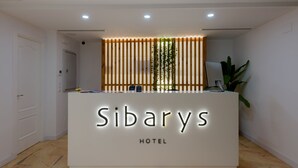 A hotel reception desk with a modern design, featuring a nameplate that reads "Sibarys HOTEL."