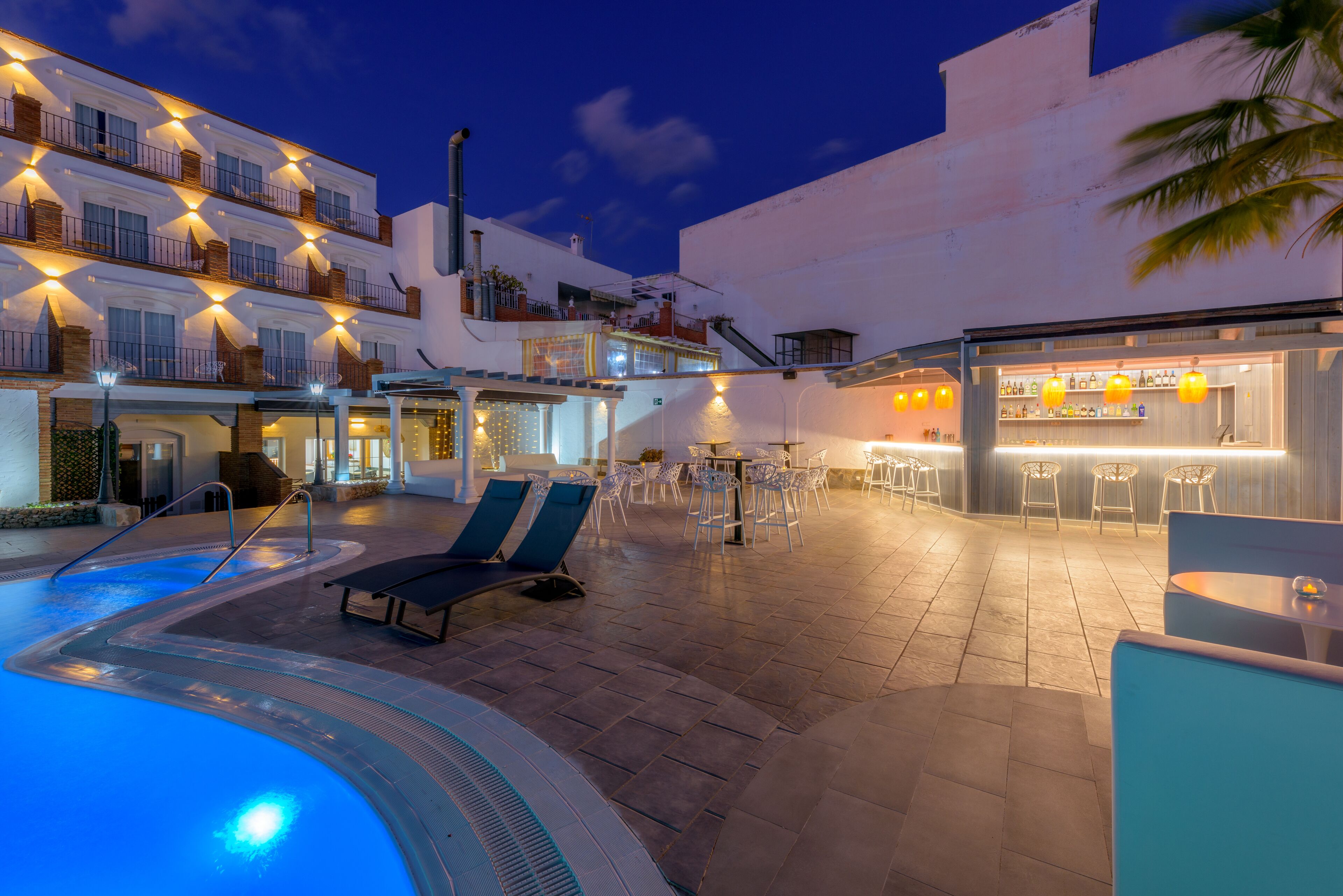 A pool area with lounge chairs, a bar, and a restaurant.