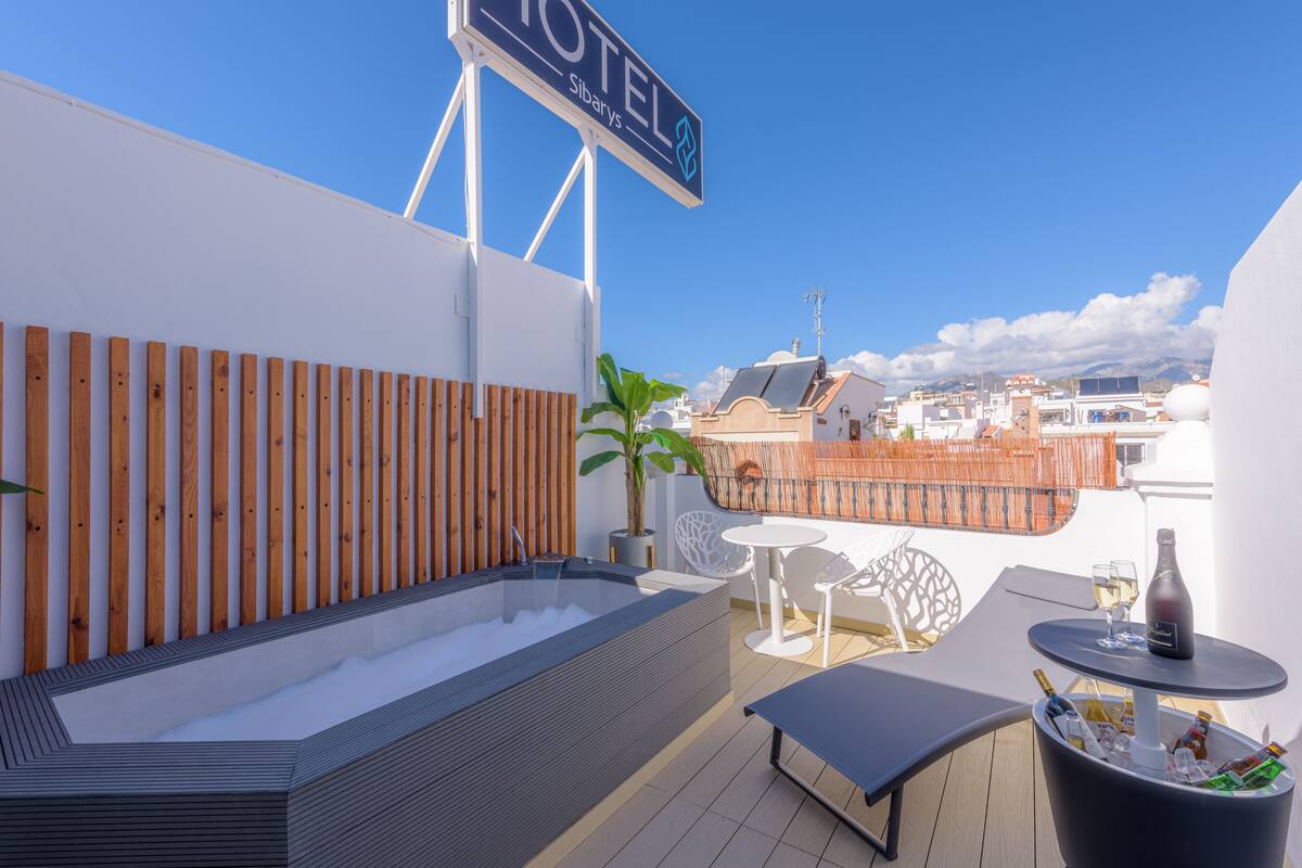 Une terrasse sur le toit équipée d’un jacuzzi, d’un coin salon et d’une table avec des boissons.