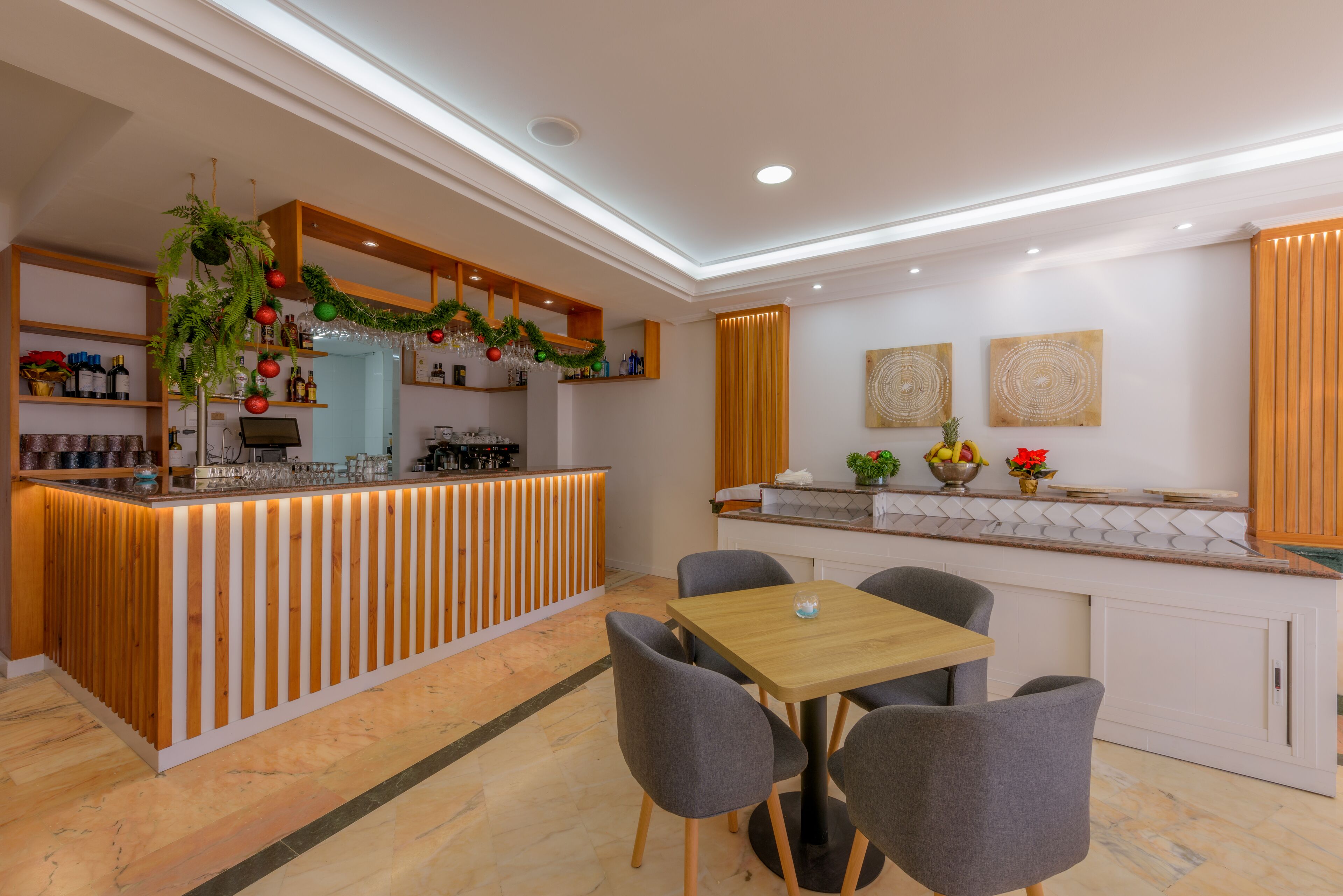 Una cocina moderna con barra de madera, mesa de comedor con sillas y encimera con diversos objetos.