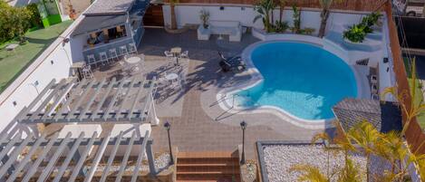 A rooftop pool area with a seating area, palm trees, and a view of the parking lot.