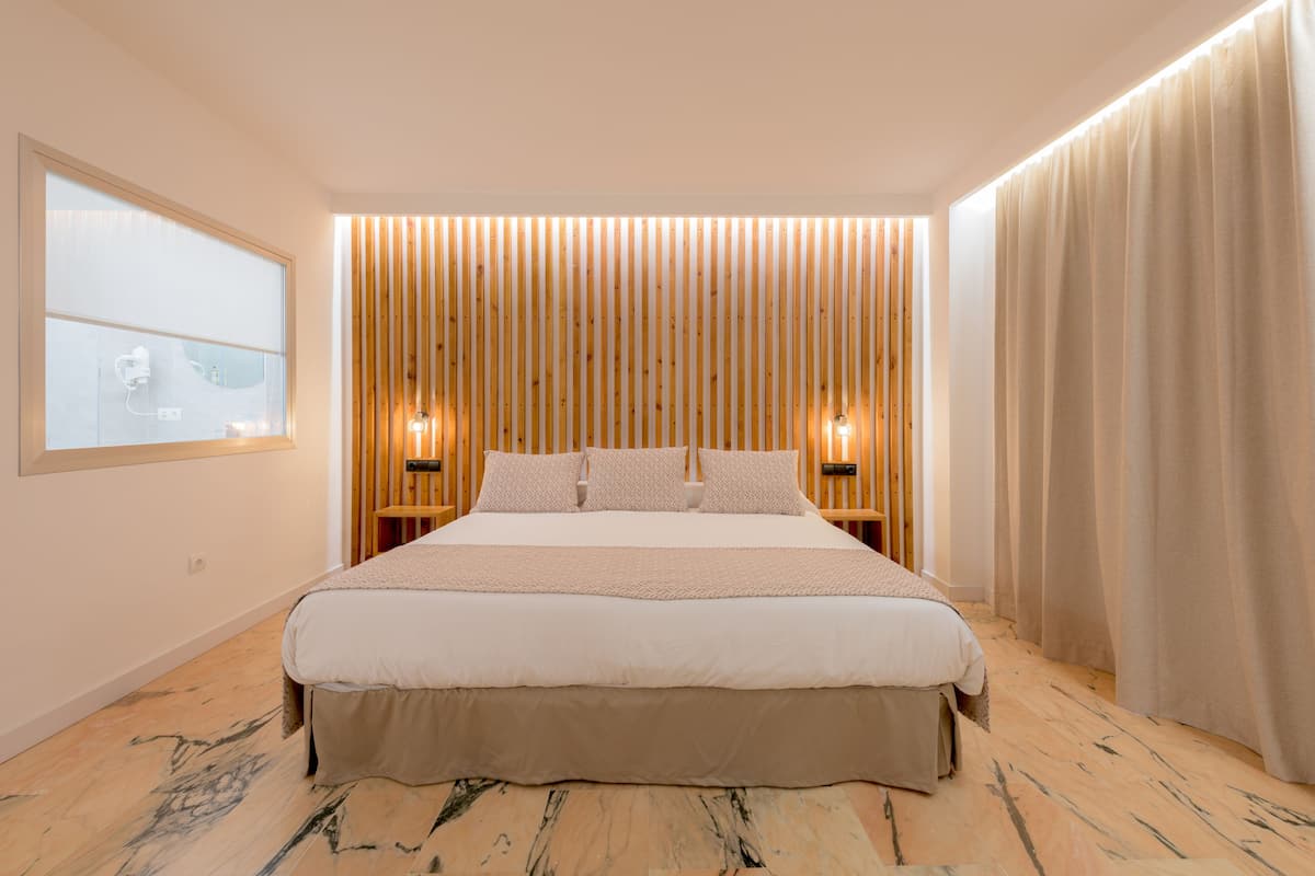 Une chambre moderne avec un grand lit, des lambris en bois au mur et deux lampes de chevet.