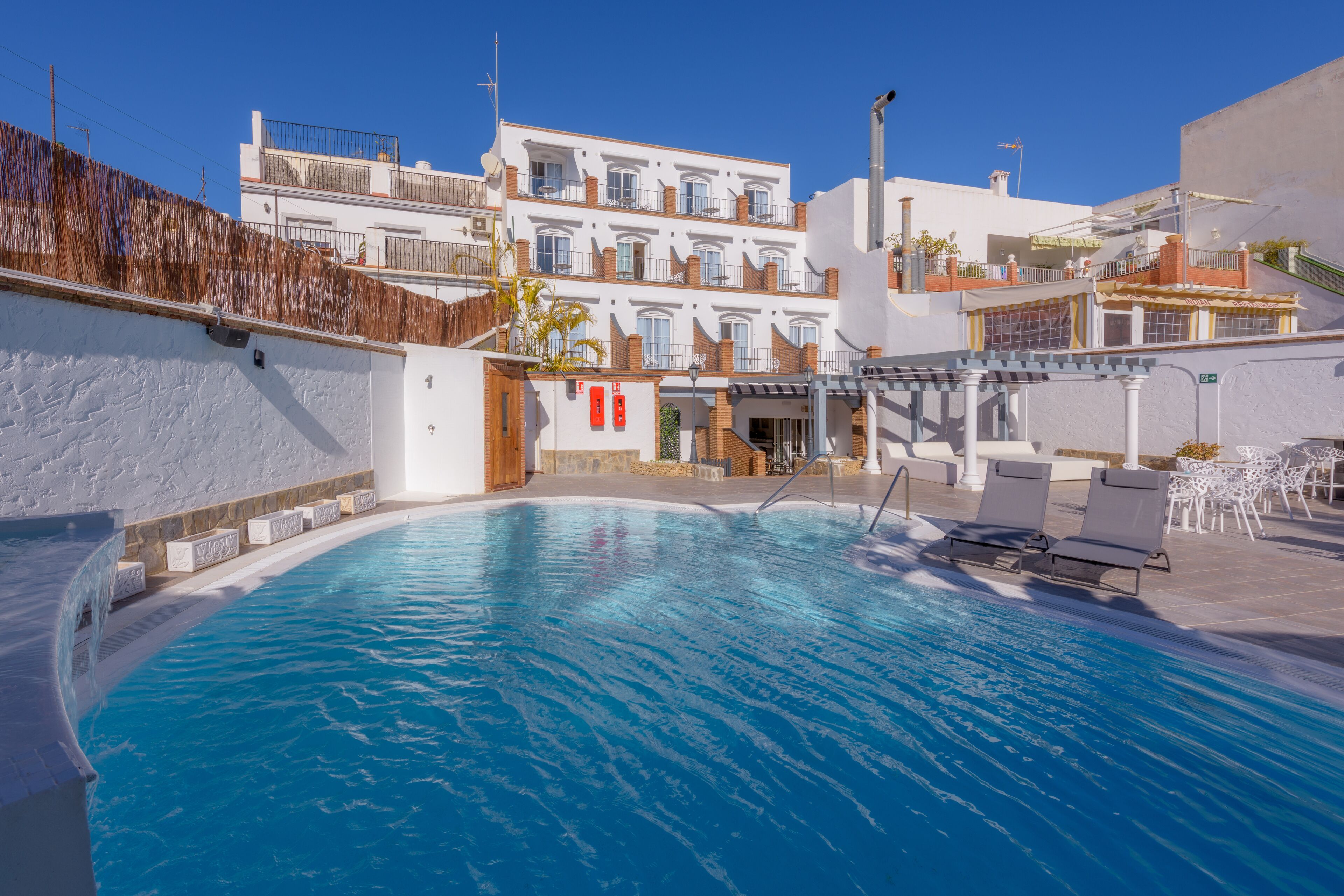 Een buitenzwembad, parasols bij het zwembad en ligstoelen